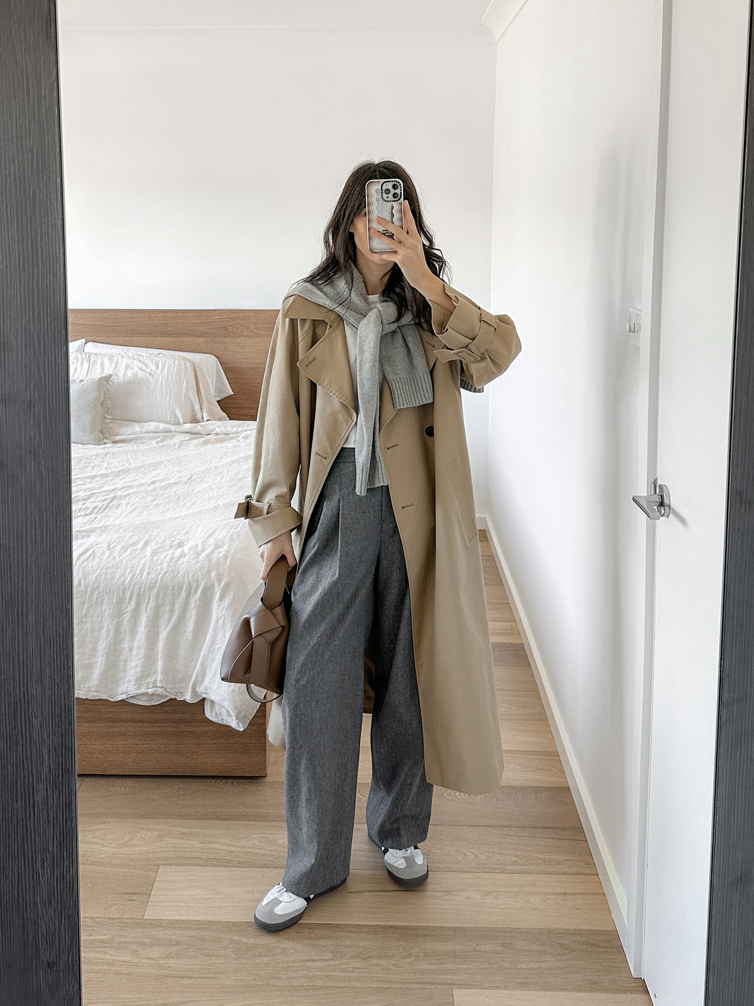 Early winter outfit ideas wearing Parisian chic trench coat with grey trousers and Adidas sambas