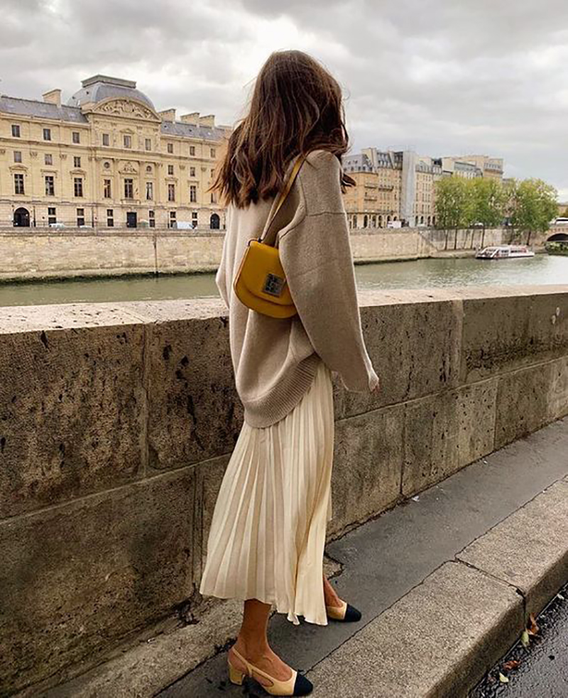 Parisian style feminine outfit with pleated skirt and oversized knit sweater