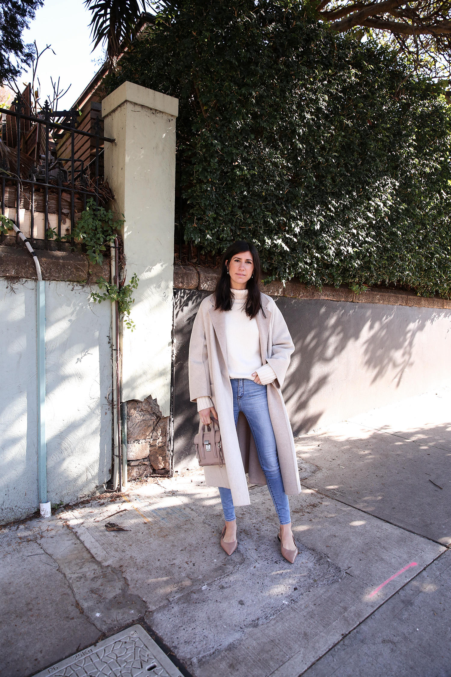 Scandi style outfit wearing white rollneck sweater skinny jeans and a duster coat