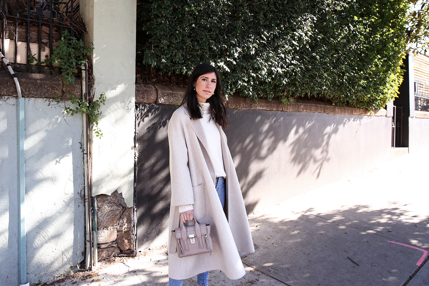 Scandi style outfit wearing white rollneck sweater skinny jeans and a duster coat