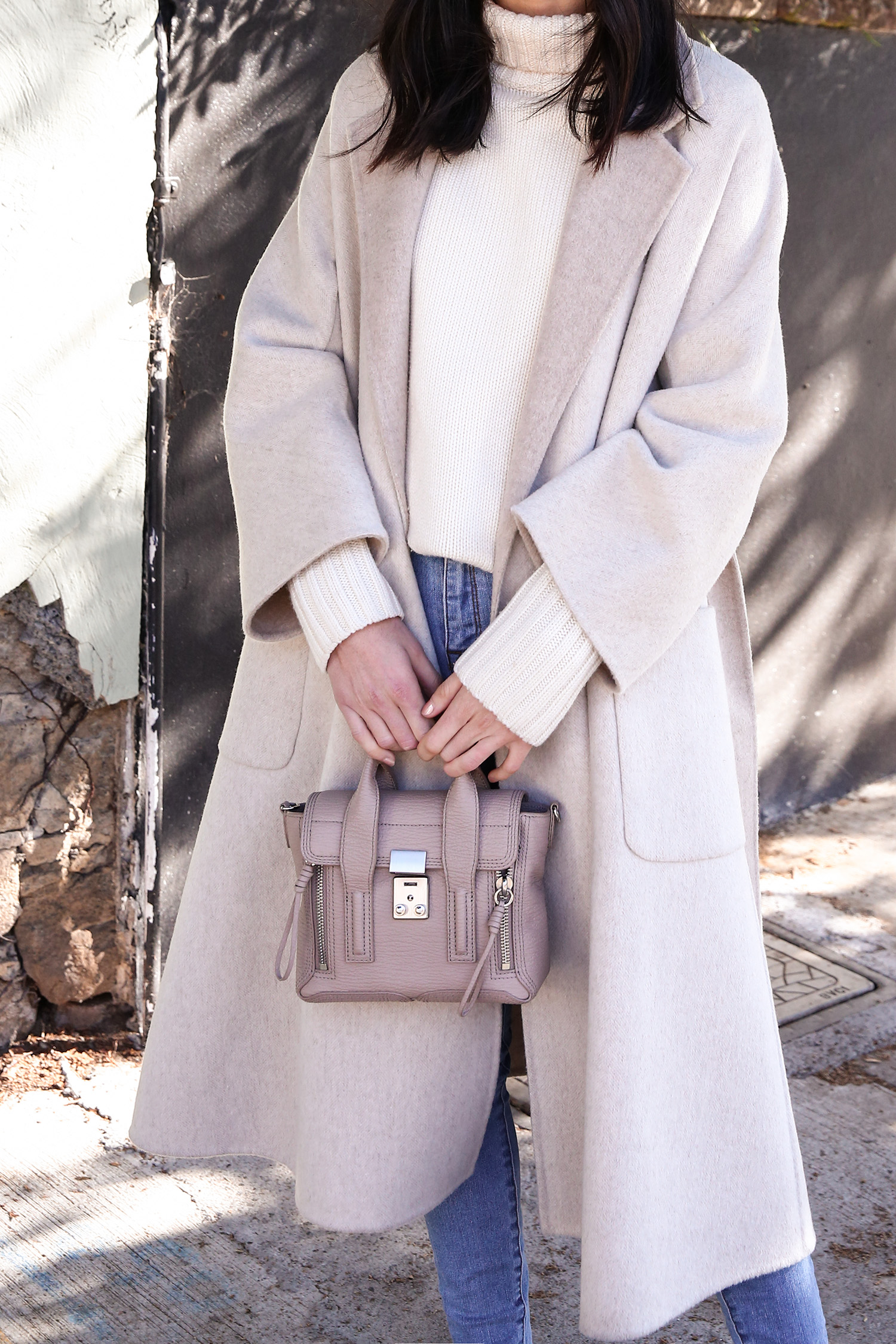 Scandi style outfit wearing white rollneck sweater skinny jeans and a duster coat