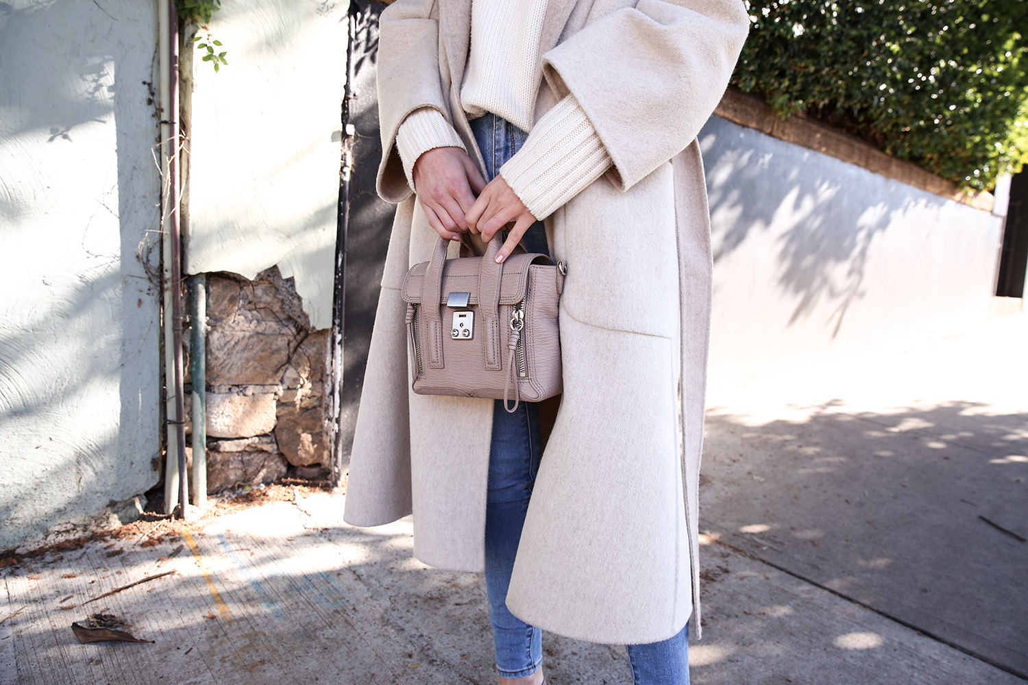 Scandi style outfit wearing white rollneck sweater skinny jeans and a duster coat