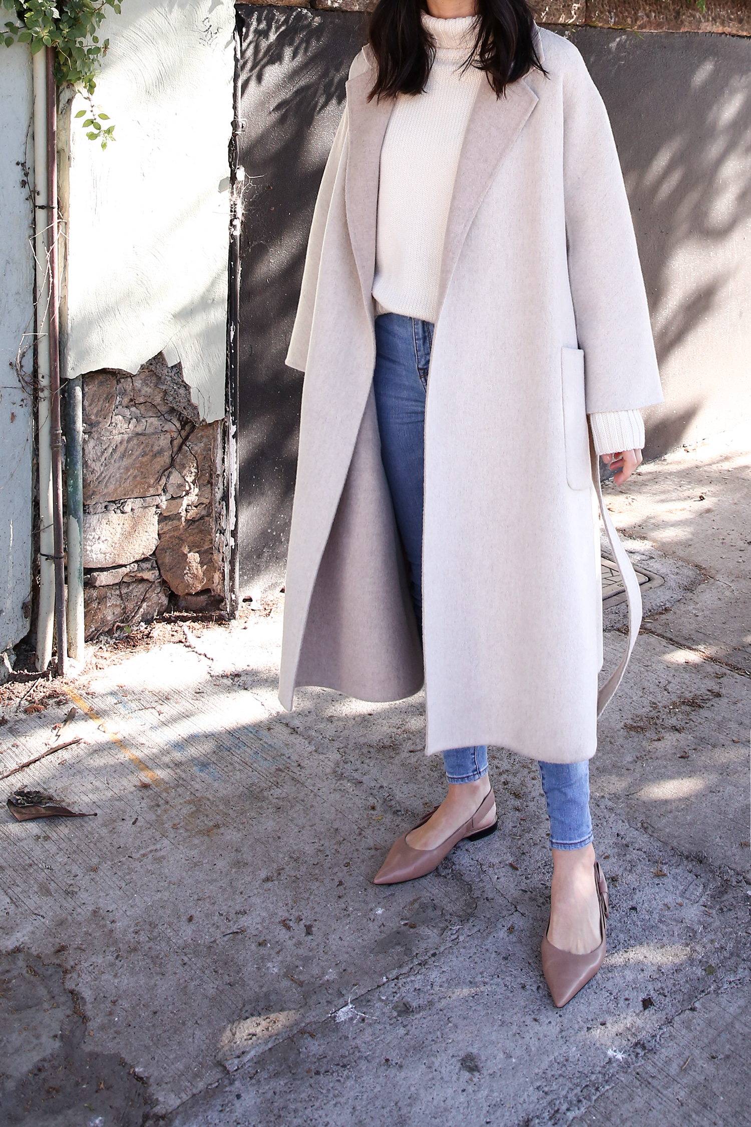 Scandi style outfit wearing white rollneck sweater skinny jeans and a duster coat