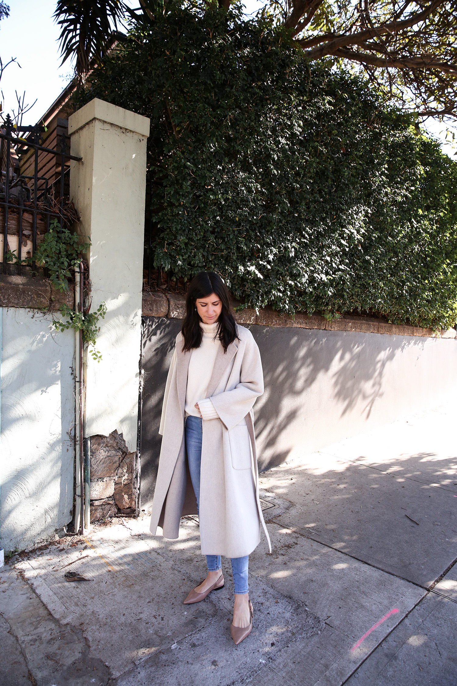 Scandi style outfit wearing white rollneck sweater skinny jeans and a duster coat