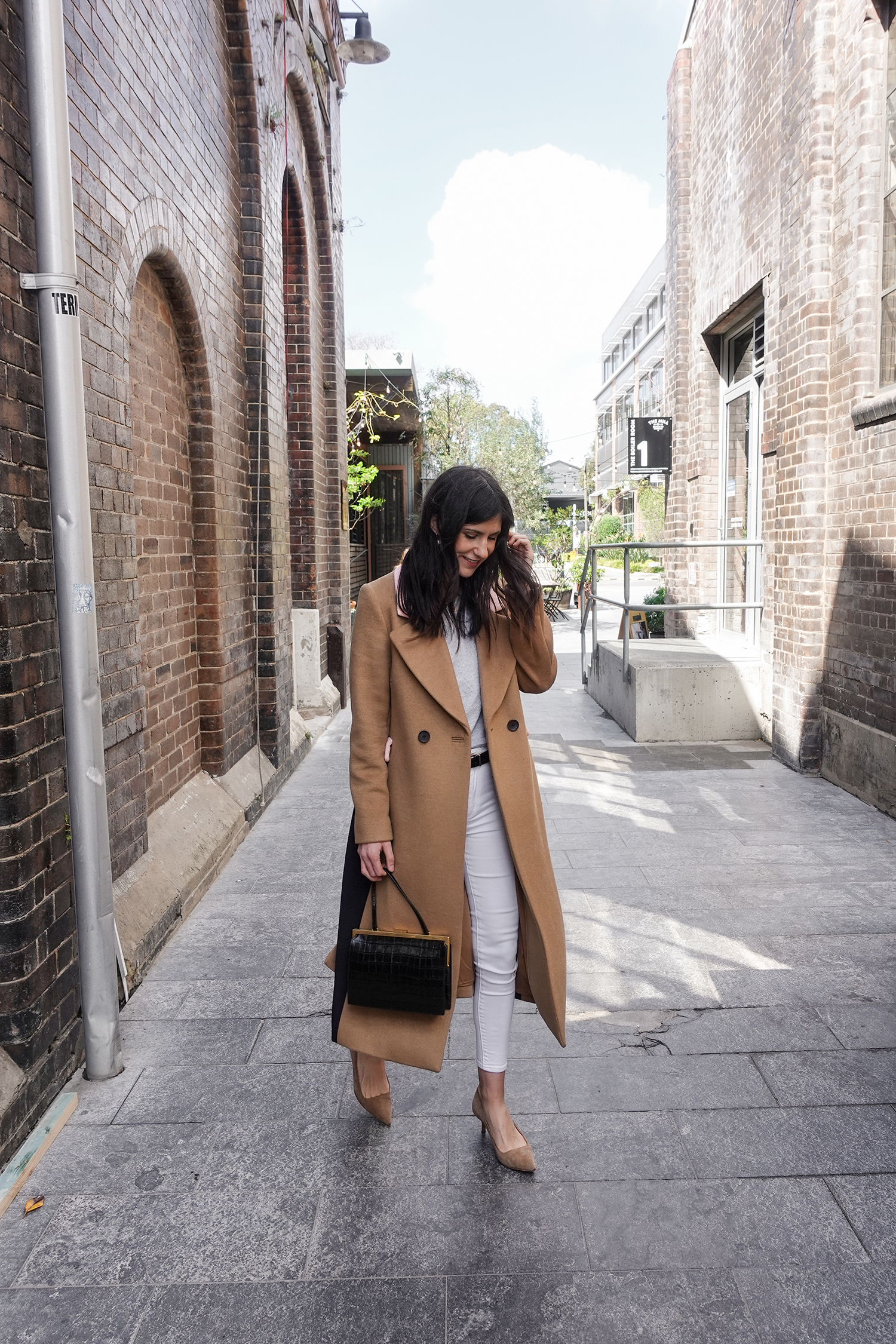 Neutral outfit in a minimal style wearing a camel coat and white jeans