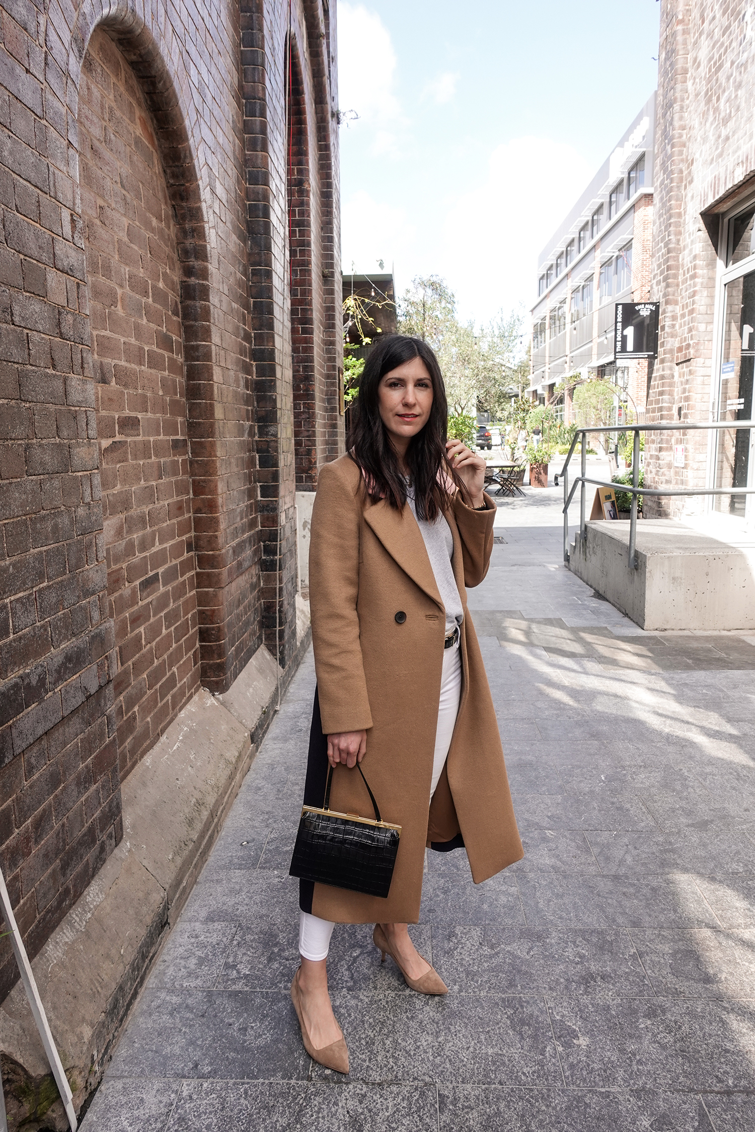 Neutral outfit in a minimal style wearing a camel coat and white jeans