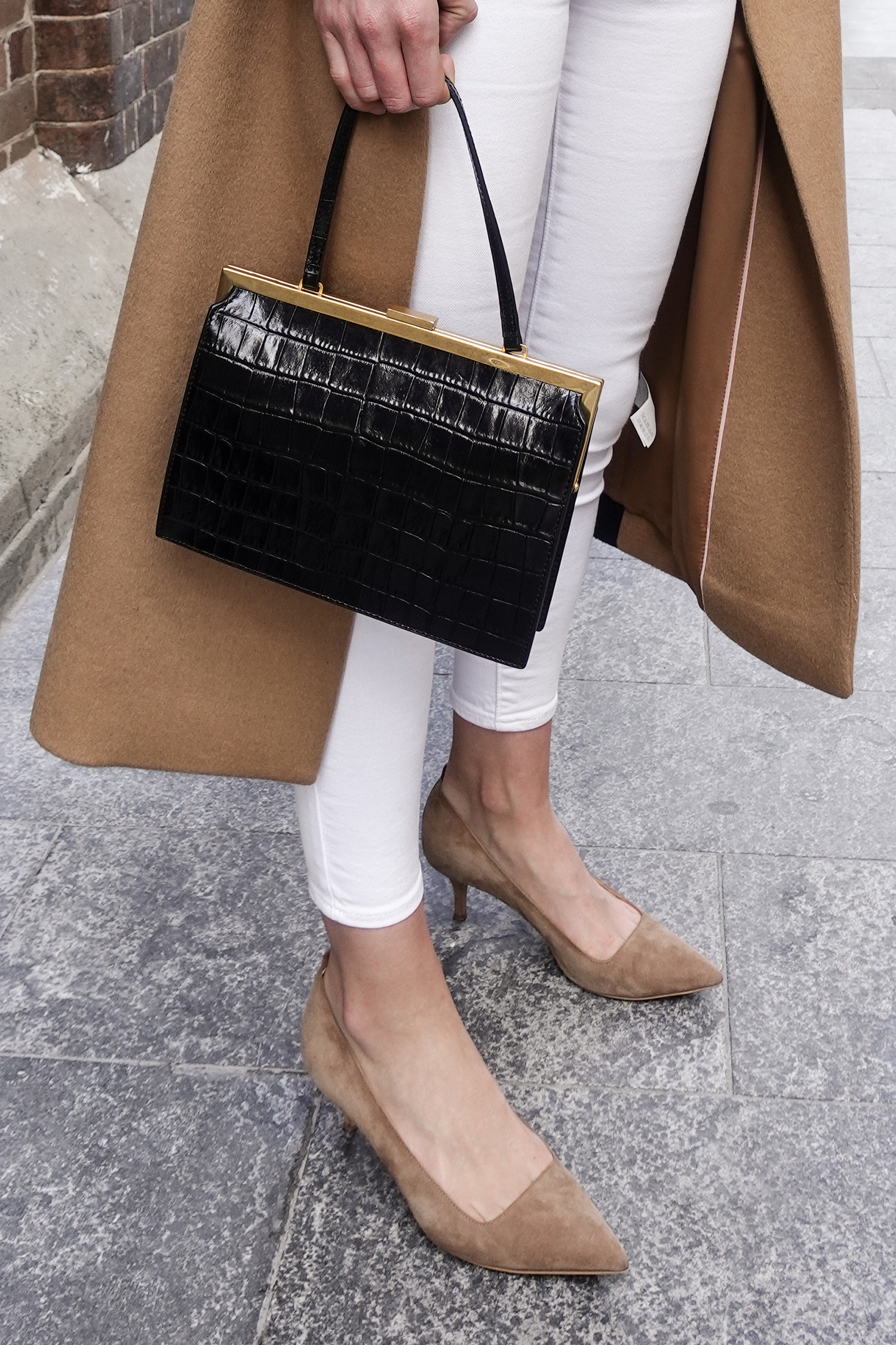 Neutral outfit in a minimal style wearing a camel coat and white jeans