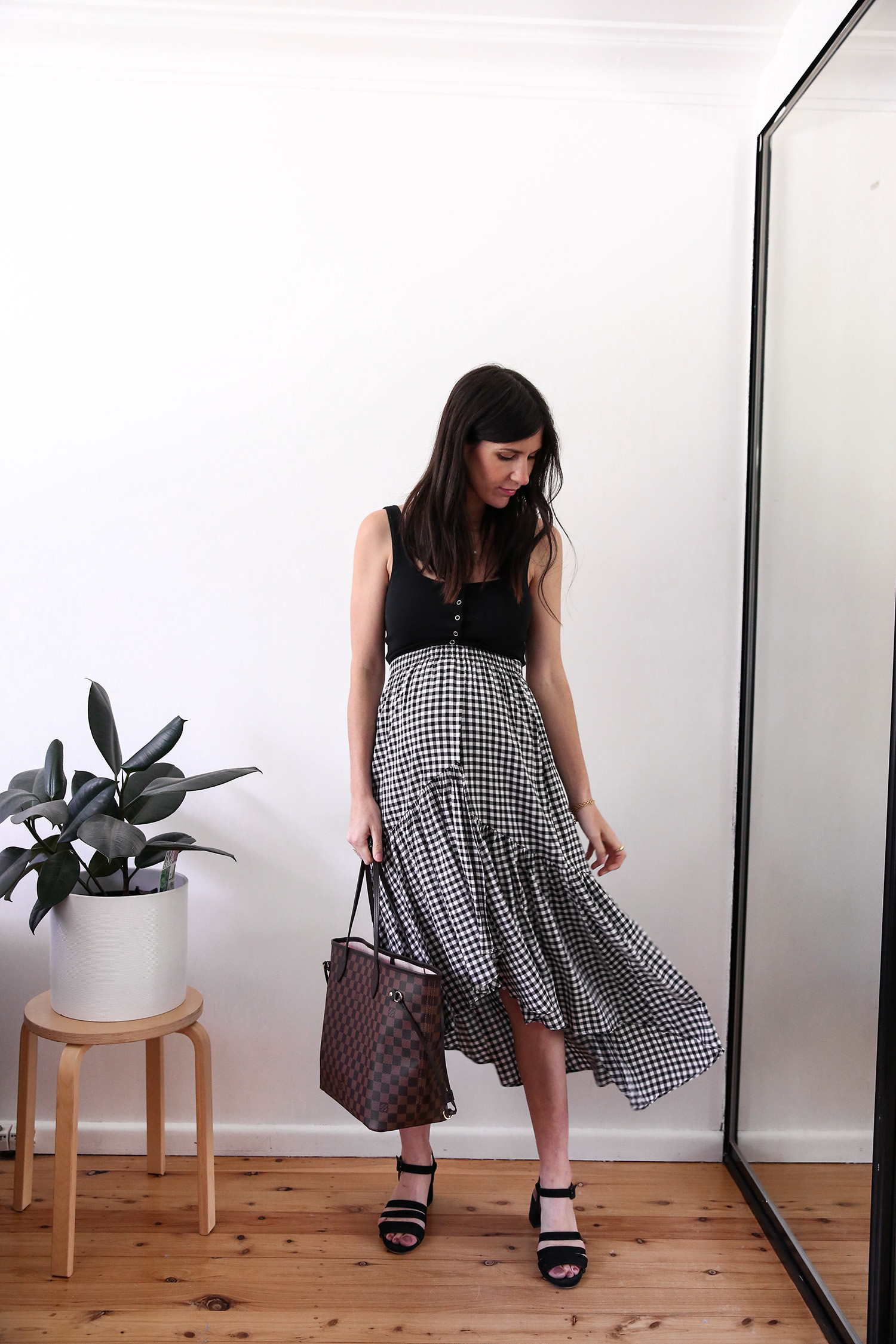 Maternity style wearing a black tank and gingham midi skirt