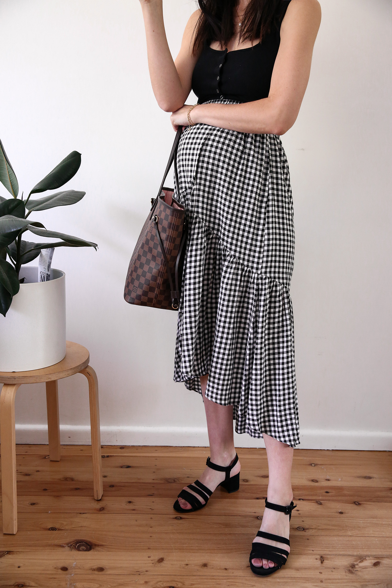 Maternity style wearing a black tank and gingham midi skirt