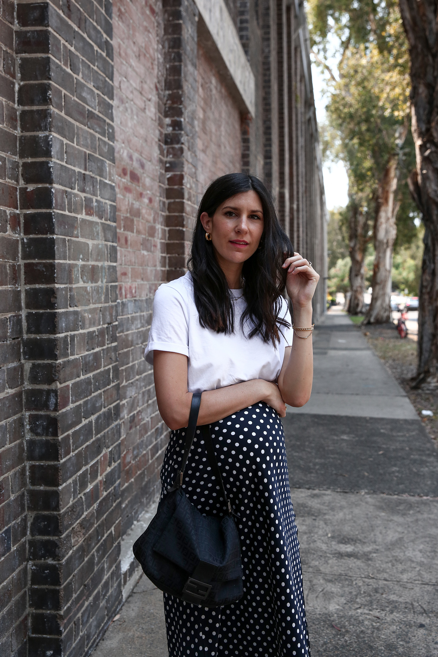 Jamie Lee of Mademoiselle wearing a white t shirt and polka dot midi skirt, minimal style, pregnancy style