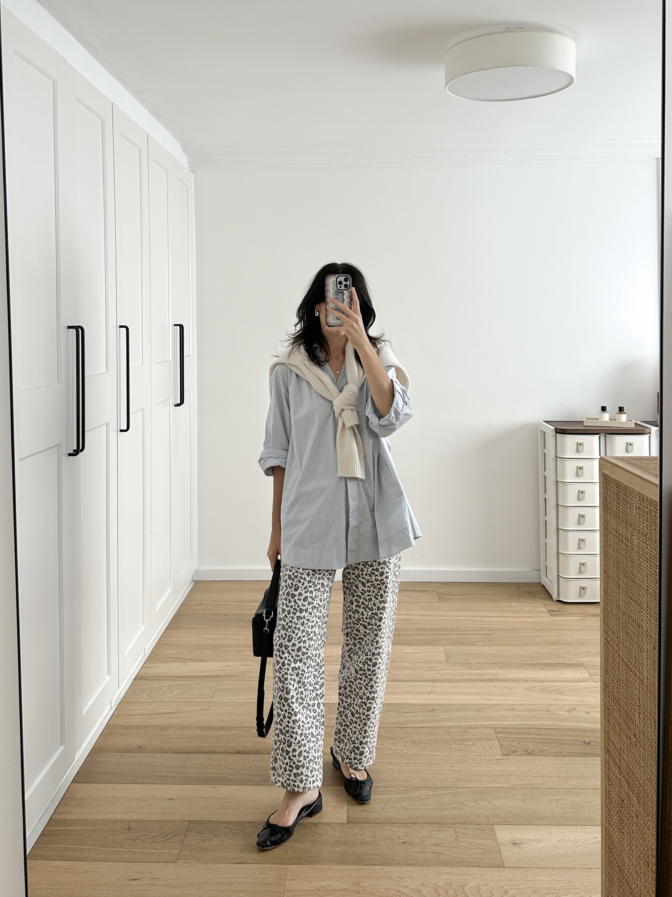 Neutral toned styling of leopard print jeans with a light blue shirt and ballet flats
